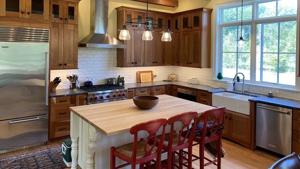Une cuisine moderne avec des meubles en bois, des appareils électroménagers en acier inoxydable et des luminaires suspendus.