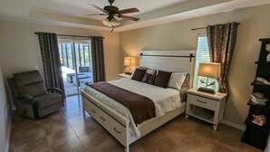 A bedroom with a bed, two bedside tables, a chair, and a ceiling fan.