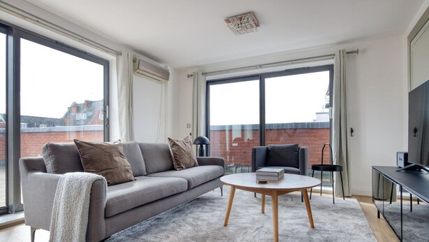 A modern living room with a grey sofa, a round coffee table, and a TV stand.