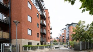 A multi-story residential building with brick exterior, balconies, and a gated entrance.