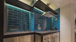 Una cocina moderna con salpicadero de azulejos azules, electrodomésticos de acero inoxidable y encimera negra.