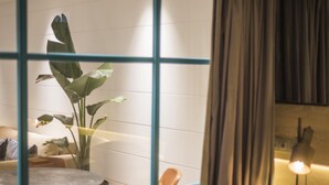 Una habitación con una mesa de comedor, sillas, una planta en maceta, una lámpara y una cortina.