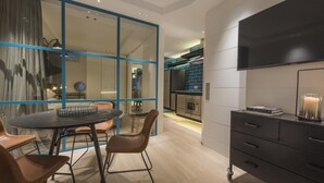 Una cocina moderna con horno empotrado, un televisor de pantalla plana grande y una zona de comedor con una mesa redonda y sillas.