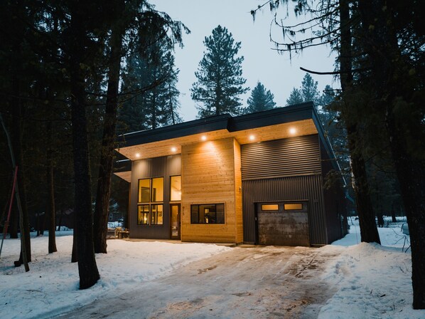A modern cabin with large windows and a wooden exterior, surrounded by snow and trees. - FINE PINE PLACE in town / luxury modern / wow kitchen / whole house / yes dogs! (McCall)