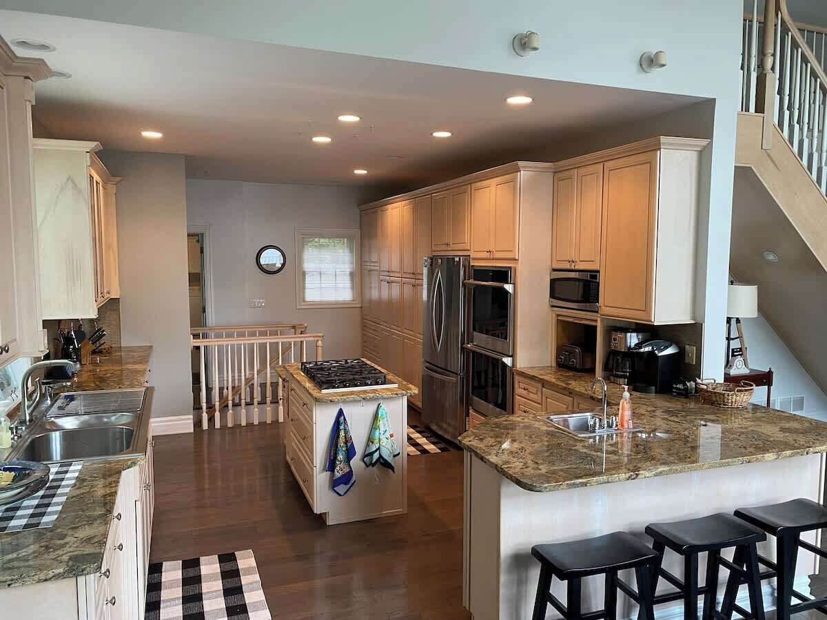 A modern kitchen with granite countertops, stainless steel appliances, and a central island with stools.