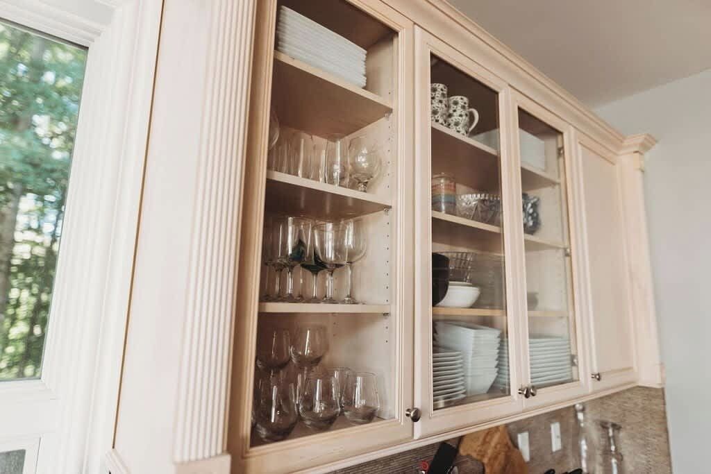 A kitchen with wooden cabinets containing glassware and dishes.