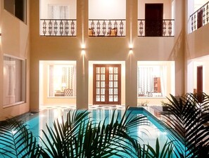 Una gran piscina interior con vistas a un balcón y una puerta con paneles de vidrio.