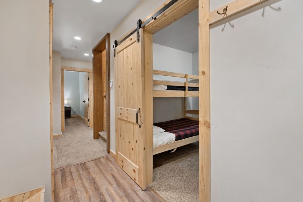 A room with a bunk bed, wooden sliding doors, and a carpeted floor.