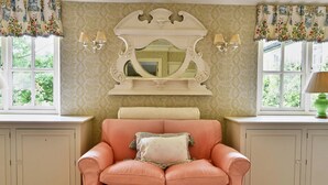 Une pièce avec un canapé en cuir de couleur pêche, un grand miroir doté d’un cadre décoratif et deux appliques murales.