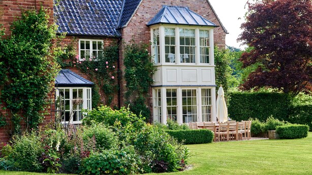 Une maison à deux étages avec une façade en briques, une lucarne et une véranda.