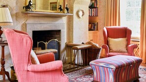 Une pièce de style traditionnel, dotée d’une cheminée, de deux fauteuils, d’un tapis à motifs et d’une bibliothèque.