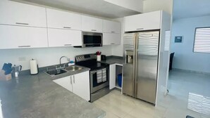 A modern kitchen with white cabinets, stainless steel appliances, and a grey countertop. - Casa LindaMaria 4 mins from the airport 6 mins from isla verde (Carolina)