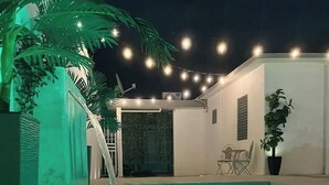 A swimming pool with a water feature, surrounded by potted plants and string lights. - Casa LindaMaria 4 mins from the airport 6 mins from isla verde (Carolina)