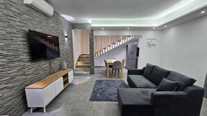 Una sala de estar moderna con un sofá seccional gris, un mueble de televisión de madera y un tapete gris.