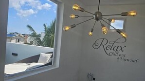 A room with a large window, a ceiling light fixture, and a wall sign that reads "Relax Chill out & Unwind".