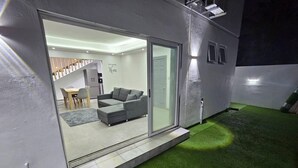 Una casa moderna con un ventanal corredero que da a un espacio de estar con un sofá y una mesa de comedor.