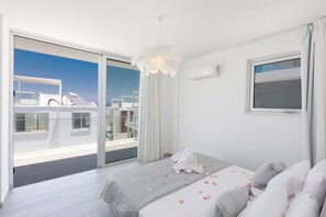 Ett hotellrum med balkong, en säng täckt av rosenblad och utsikt över havet.