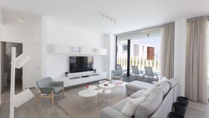 A modern living room with a large TV, comfortable seating, and a balcony with outdoor furniture. - Protaras Olivine Villa OL9 - Beautiful 4BDR Protaras Villa with Private Pool (Protaras)