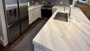 A modern kitchen with stainless steel appliances, white cabinetry, and a marble countertop. - Updated Canyons condo steps from Cabriolet lift - full kitchen, washer/dryer (Park City)