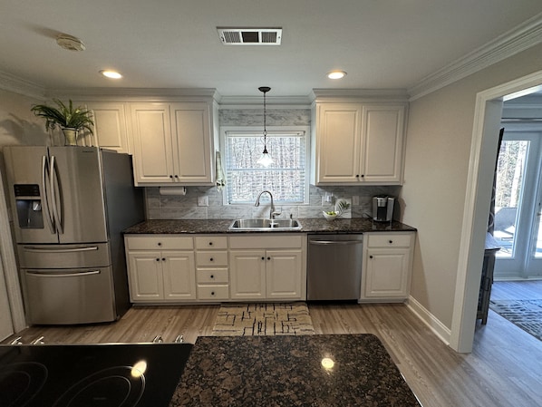 A modern kitchen with white cabinets, a stainless steel refrigerator, a built-in oven, a sink, and a coffee maker. - Beautiful 2BR 1BA - Atlanta's Best Location & Amenities (Atlanta)