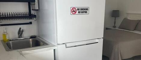 A compact kitchen with a built-in sink, a white refrigerator, and a small countertop with a soap dispenser.