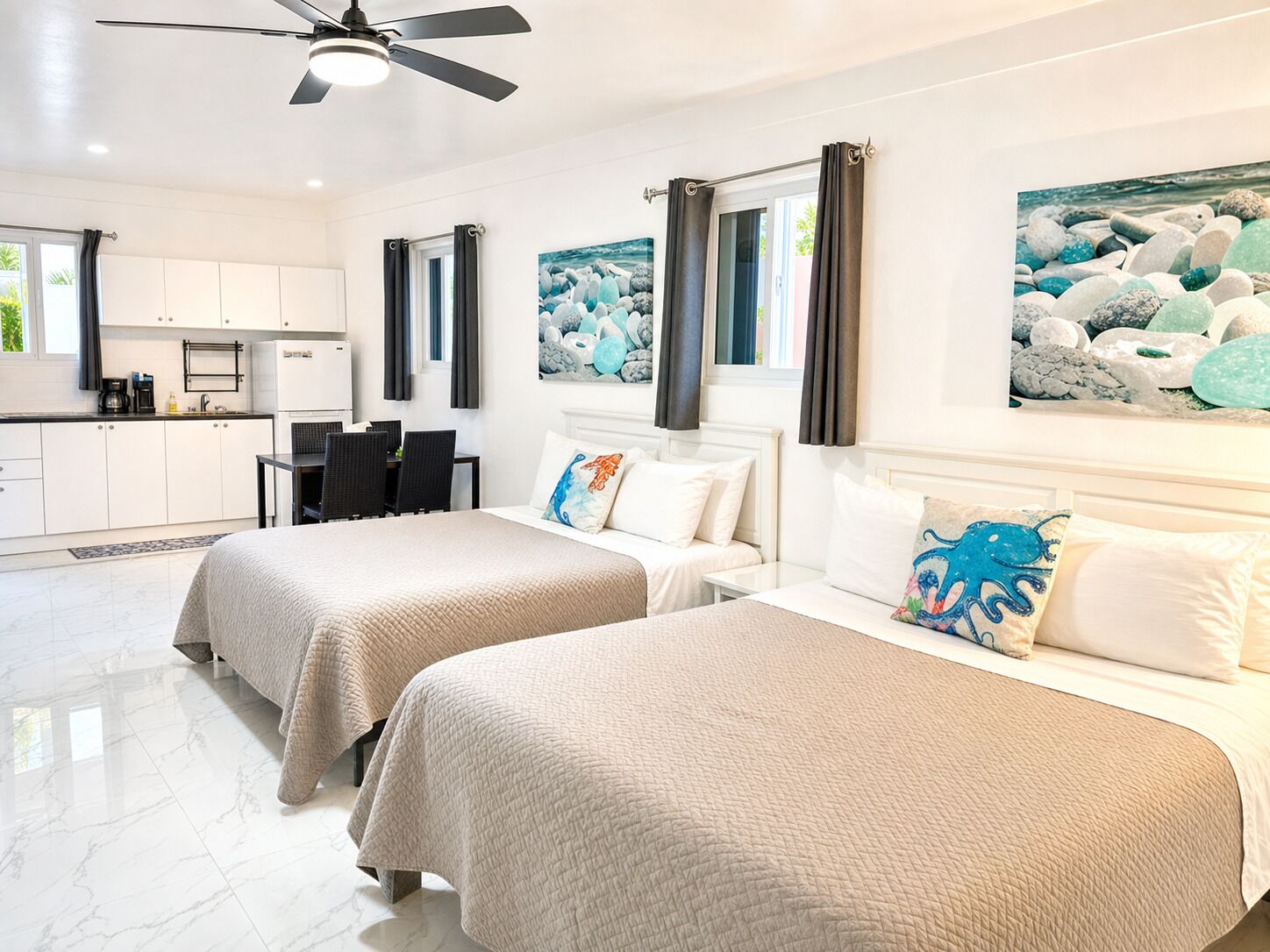 A hotel room with two beds, a dining area, and a kitchen.