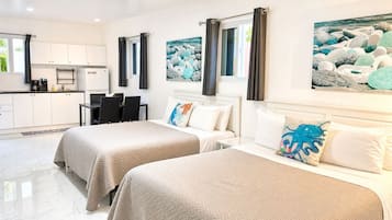 Een hotelkamer met twee bedden, een eethoek en een keuken.