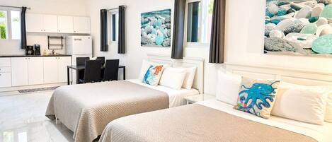 A hotel room with two beds, a dining area, and a kitchen.