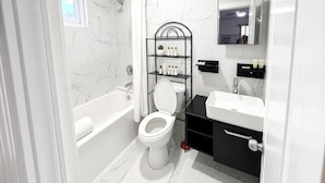 A bathroom with a bathtub, toilet, and a vanity with a mirror.