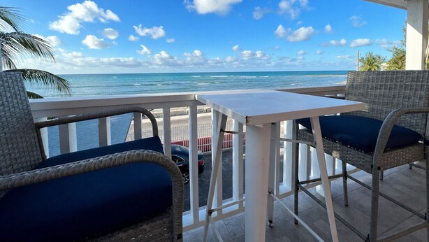 A balcony with wicker furniture and a view of the ocean. - The Sunset Stay BnB (Nassau)