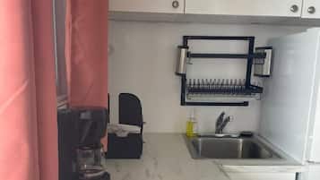 Una cocina compacta con estufa integrada, cafetera, lavabo y un espacio para especias.