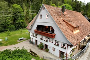 Une maison à deux étages avec un toit en pente, un balcon et un petit jardin.