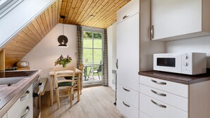 Une cuisine équipée d’un four à micro-ondes, avec un plafond en bois et un coin repas comprenant une table et des chaises.