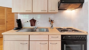 A kitchen with wooden cabinets, a stainless steel sink, a coffee maker, and a stove.