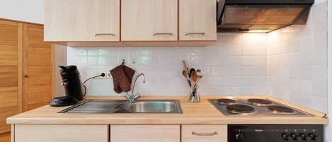 A kitchen with wooden cabinets, a stainless steel sink, a coffee maker, and a stove.