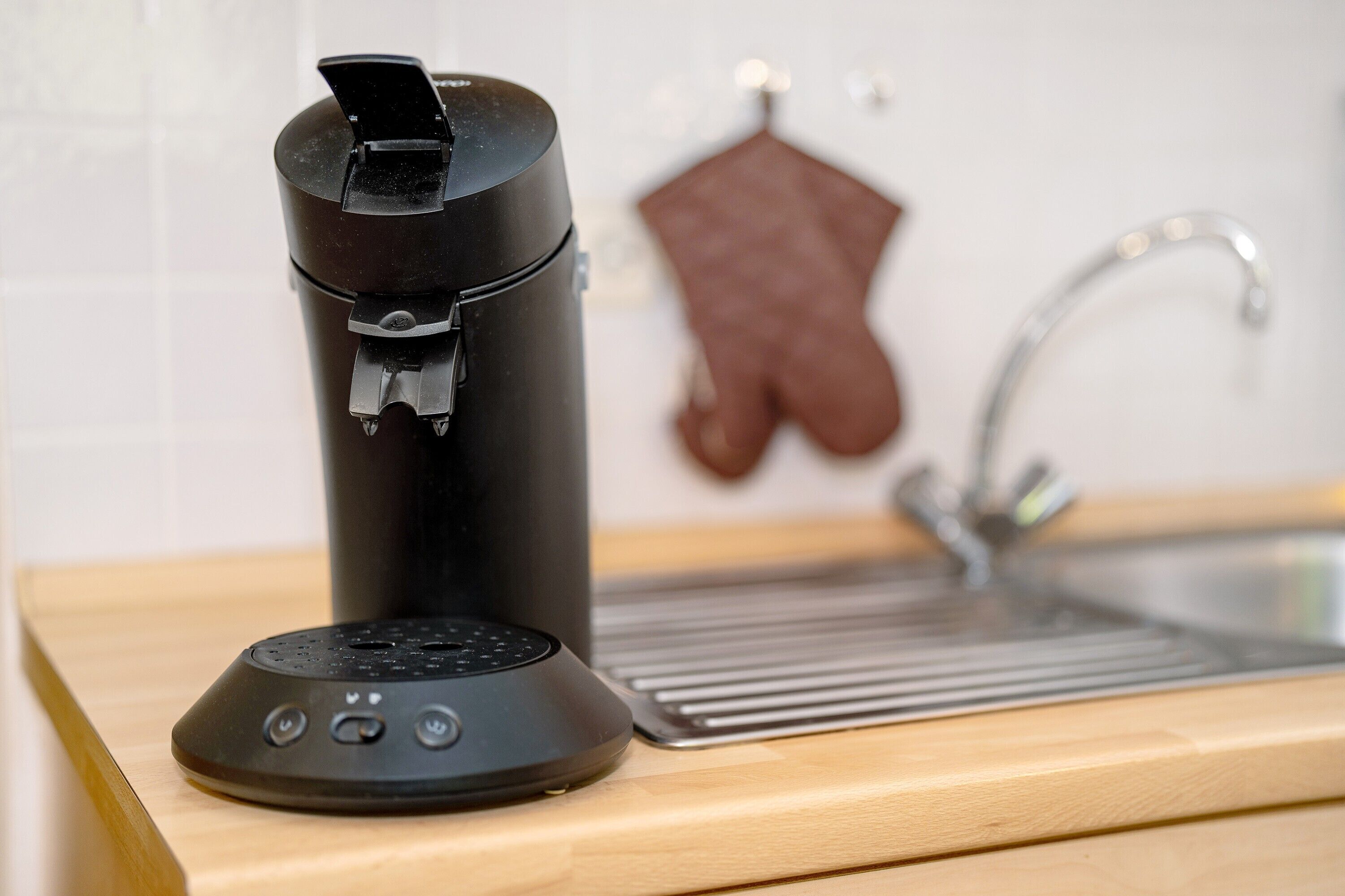 Een keuken met een koffiezetapparaat, een spoelbak en een houten aanrecht.