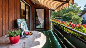 A wooden balcony with a table, a chair, and a potted plant. - Haus Berger Ferienwohnung 2 (Wehr)