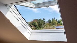 A skylight window with a view of trees and solar panels. - Haus Berger Ferienwohnung 2 (Wehr)