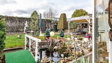 Ein Garten mit Teich, Statue und verschiedenen Pflanzen.