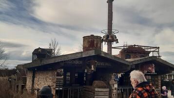 Ein rustikales Gebäude mit einem Schild, auf dem 'LIEGENDER' steht, und einer großen Skulptur einer Kuh.