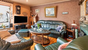 Una sala de estar con un sofá de cuero, una mesa de centro, un televisor y una chimenea.