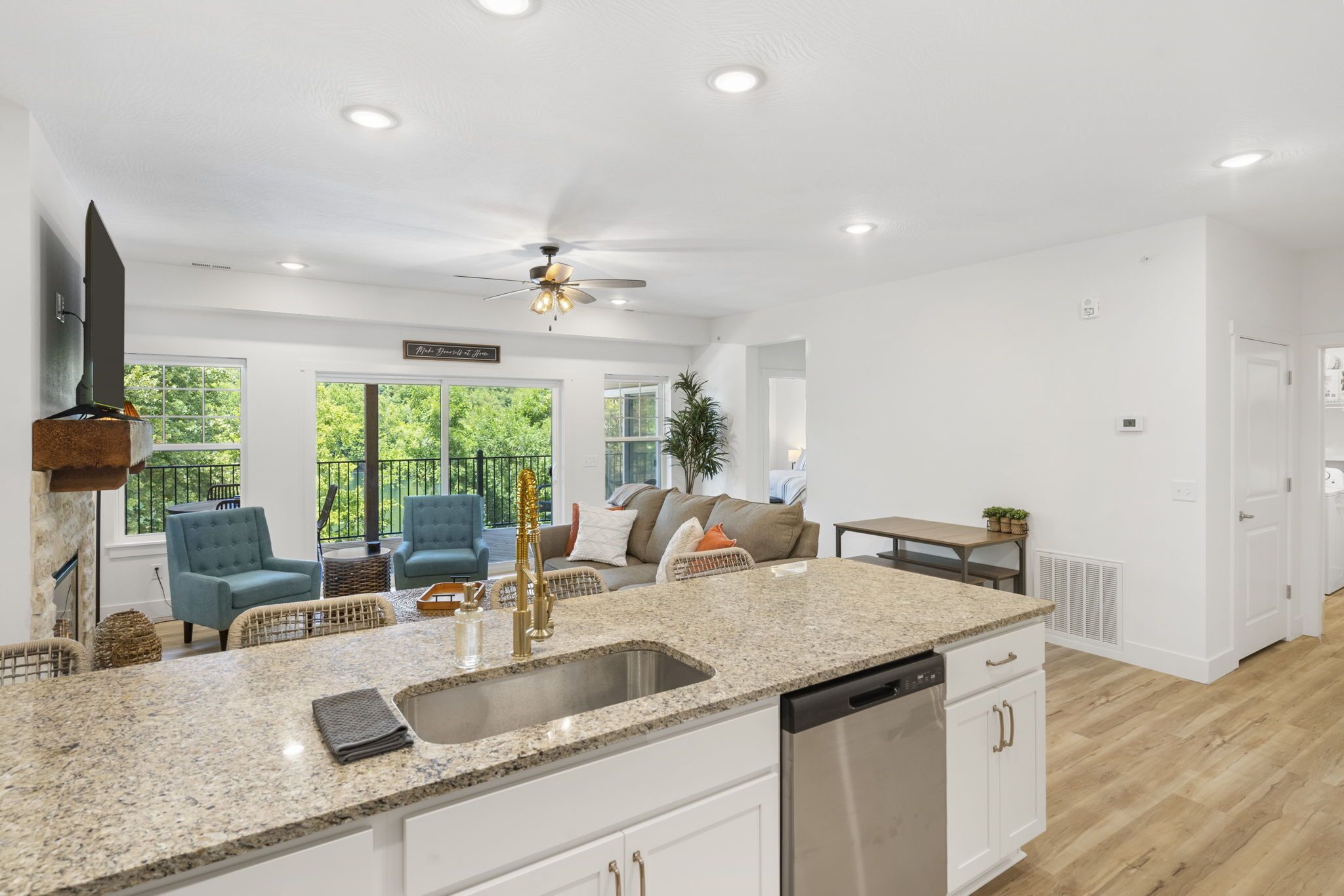 A spacious kitchen with granite countertops, stainless steel appliances, and a ceiling fan.