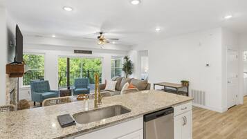 A spacious kitchen with granite countertops, stainless steel appliances, and a ceiling fan.