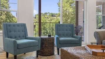 A balcony with two blue armchairs, a wicker side table, and a woven ottoman.