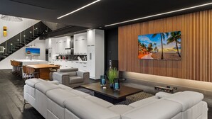 Ein modernes Wohnzimmer mit einem Ecksofa, einem Couchtisch mit dekorativen Vasen und einem großen Flachbildfernseher, der an einer Holzvertäfelung befestigt ist.