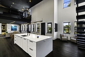Uma cozinha moderna com uma ilha grande, piso de madeira escura e um mezanino com assentos.