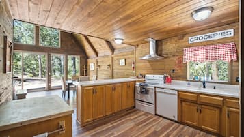 Cocina de cabaña de madera con un ventanal grande, un comedor y un letrero que dice 'GROCERIES'.