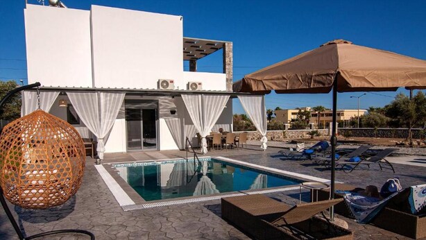 A swimming pool with lounge chairs and a covered seating area.