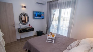 A bedroom with a bed, a bedside table, a TV, and a window with curtains.