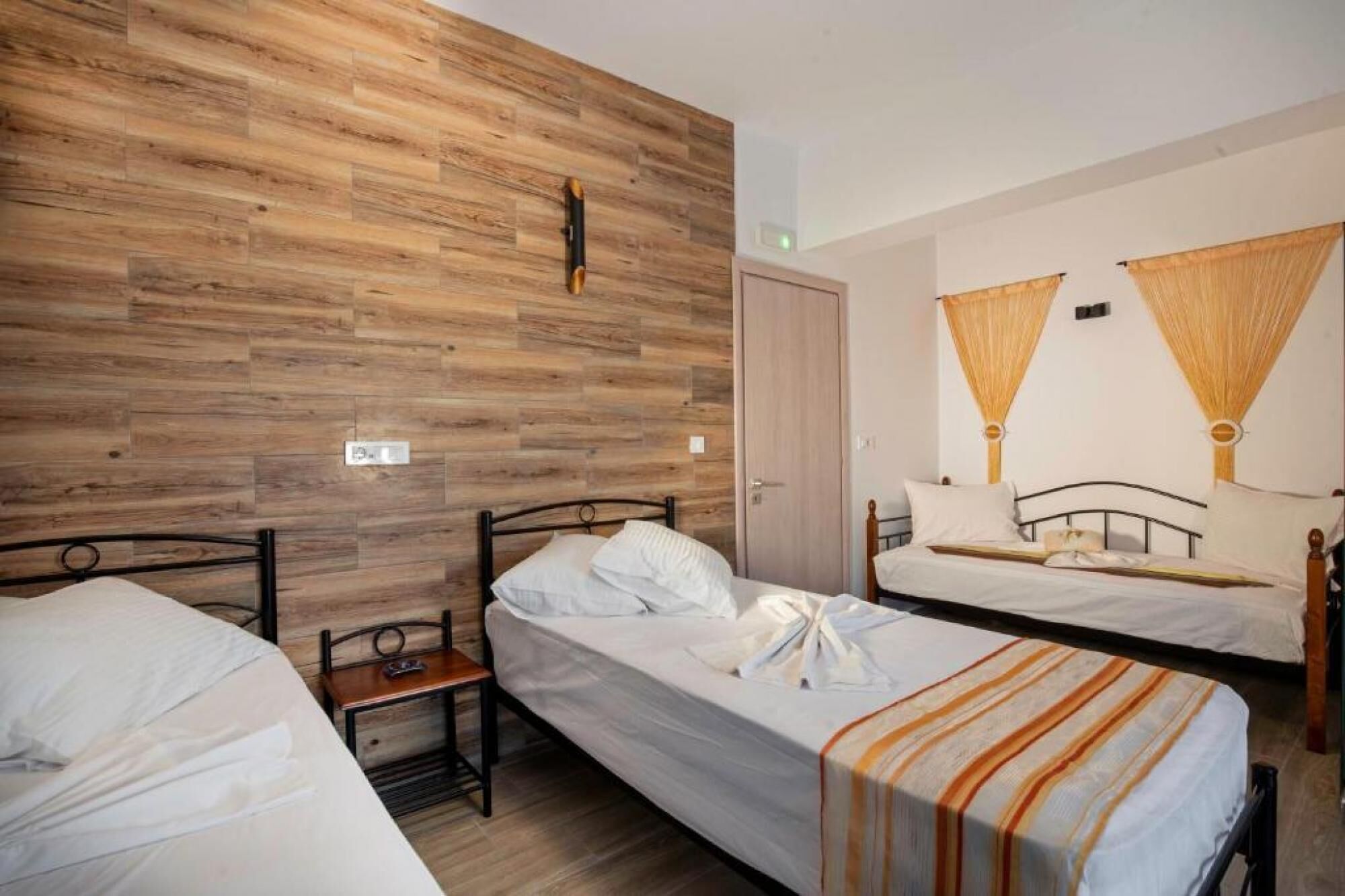 Ein Hotelzimmer mit zwei Einzelbetten, einer Wand mit Holzverkleidung und einem kleinen Nachttisch.